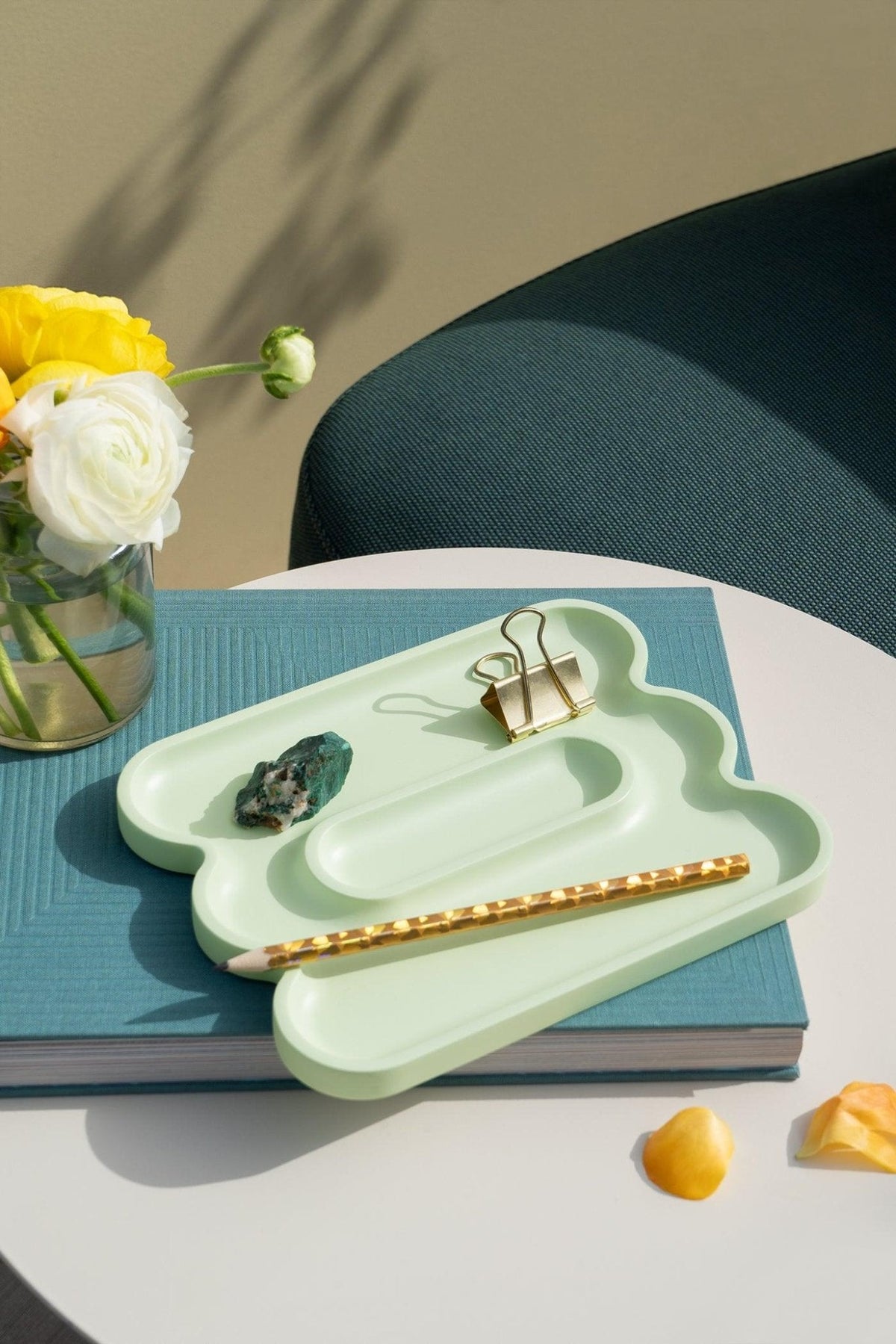OCTAEVO Templo Wave Catchall in pastel green holds small items on a white table near flowers and a blue book.