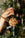 A hand holds the OCTAEVO Cinnamon Bun Ornament in front of a decorated Christmas tree.