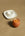 The OCTAEVO Soft-Boiled Egg Candle, shaped like an egg in an eggshell, rests by a white ceramic egg cup.