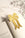 The OCTAEVO Bookmark Coquette, ribbon-shaped, rests on an open book, casting a soft shadow on marble.
