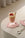 A pink and yellow dessert in a glass sits on an Octaevo Pink Anthurium Coaster, topped with crumbs and a wafer.