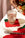 A hand sets a glass on an Octaevo Tomato Coaster (Set of 4) beside tomatoes and a knife on a white table.