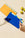A hand lifts an OCTAEVO Liguria Creative Notes dot grid notebook near yellow fruits on a beige surface.