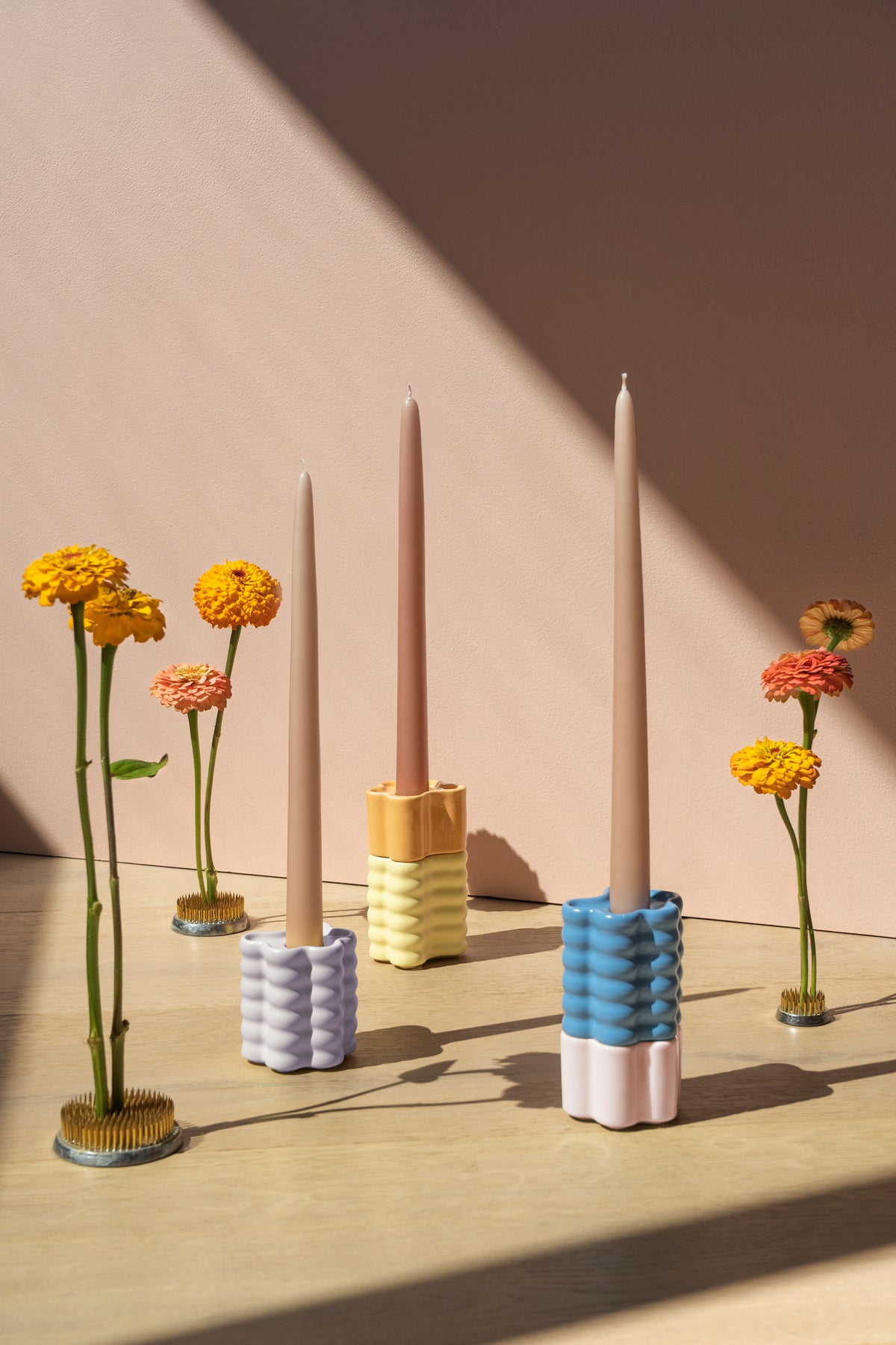 Three OCTAEVO Flora Candle Holders—Small, with taper candles and six orange blooms in glass pin frogs on wood.