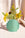 A bouquet of yellow and green flowers in the OCTAEVO Hera Mini Paper Vase against a light fabric background.