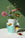 Colorful wildflowers in the OCTAEVO Siena Mini Paper Vase on white; a red bloom lies nearby against a green background.