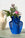 The Helio Paper Vase by OCTAEVO with blooms sits on a green table beside a beige jug against a white wall.
