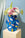 The Hamsa Paper Vase by OCTAEVO, with colorful hand patterns, holds assorted flowers on a light blue background.