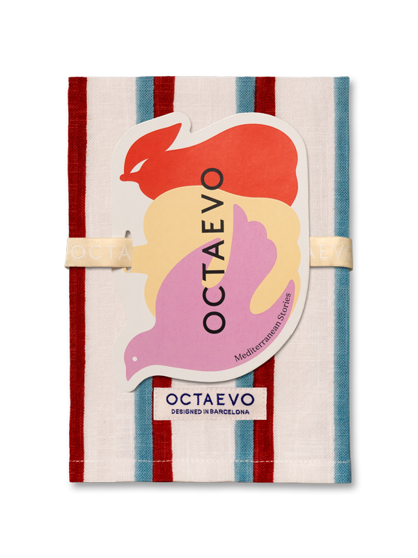 Ein gestreiftes Küchentuch mit senkrechten Bahnen in Rot und Creme, mit einem großen gestanzten Papieranhänger mit bunten abstrakten Formen und dem Markennamen OCTAEVO, befestigt mit einem cremefarbenen Gummiband.