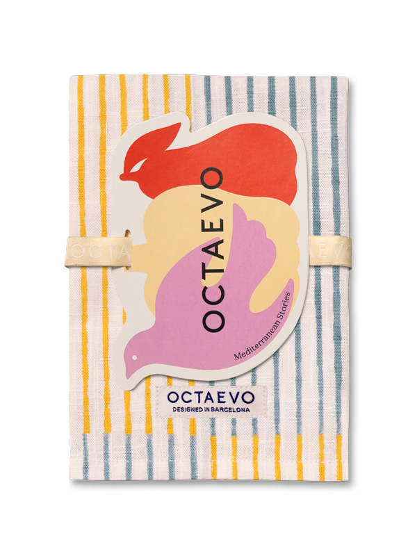Servilleta mediterránea de Octaevo con un patrón de rayas naranjas y azules, envuelta con una banda elástica beige y adornada con una pegatina gráfica colorida.
