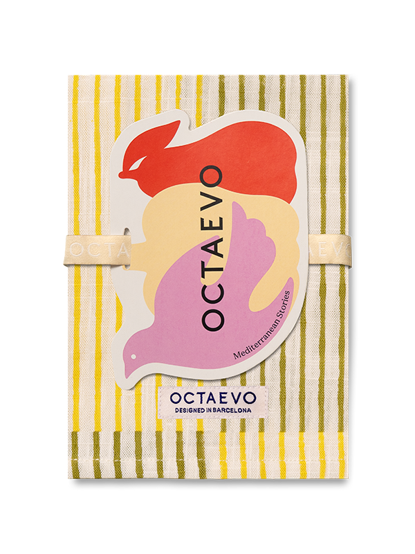 Servilleta mediterránea de Octaevo con un patrón de rayas amarillas y verde oliva, envuelta con una banda elástica beige y adornada con una pegatina gráfica colorida.