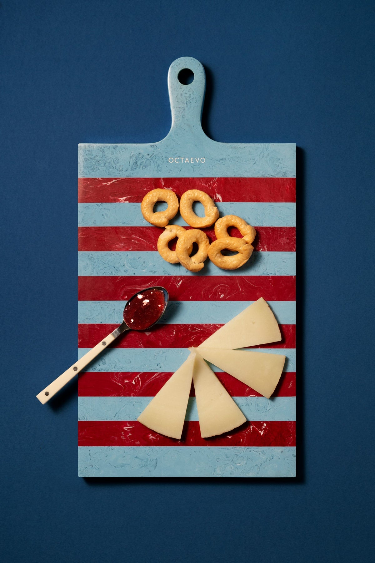 The OCTAEVO Serving Board — Burgundy & Blue displays cheese slices, bread rings, and a spoon with red sauce.