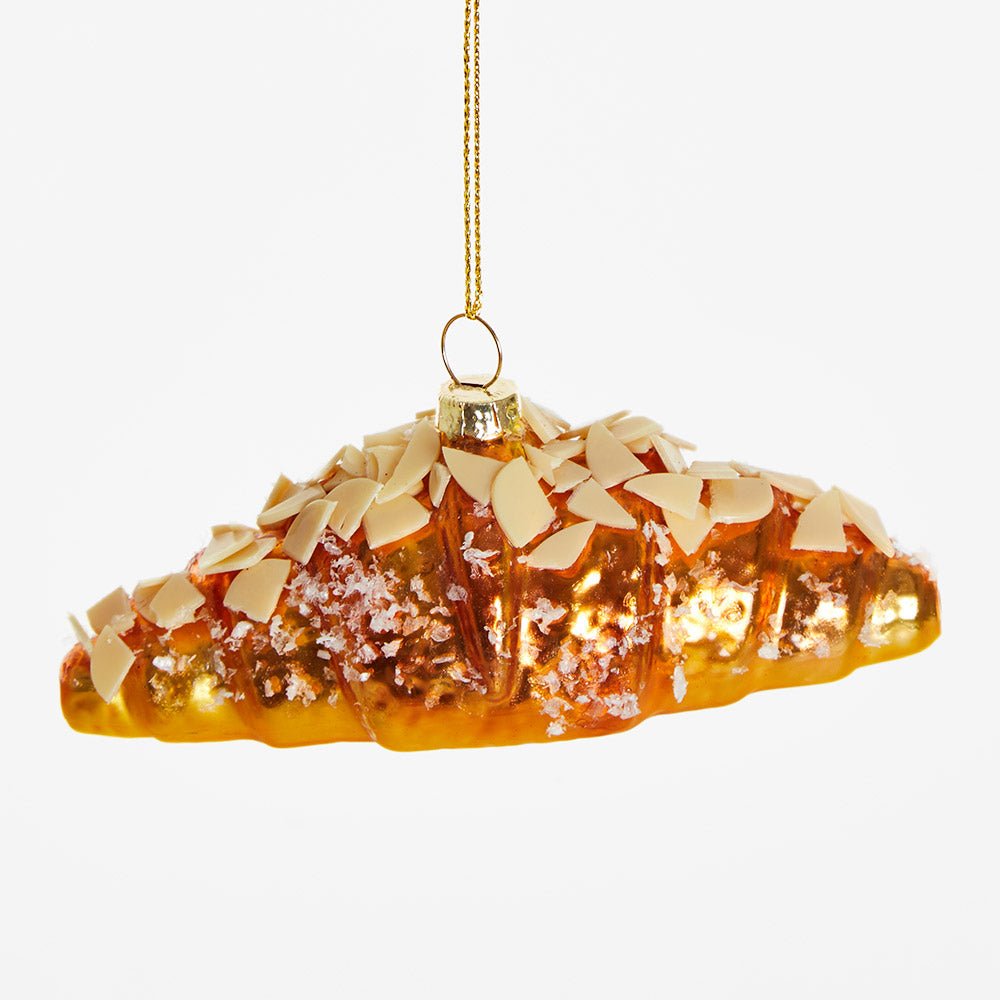 OCTAEVO Almond Croissant Ornament hangs by a gold string, perfect as a festive decoration.