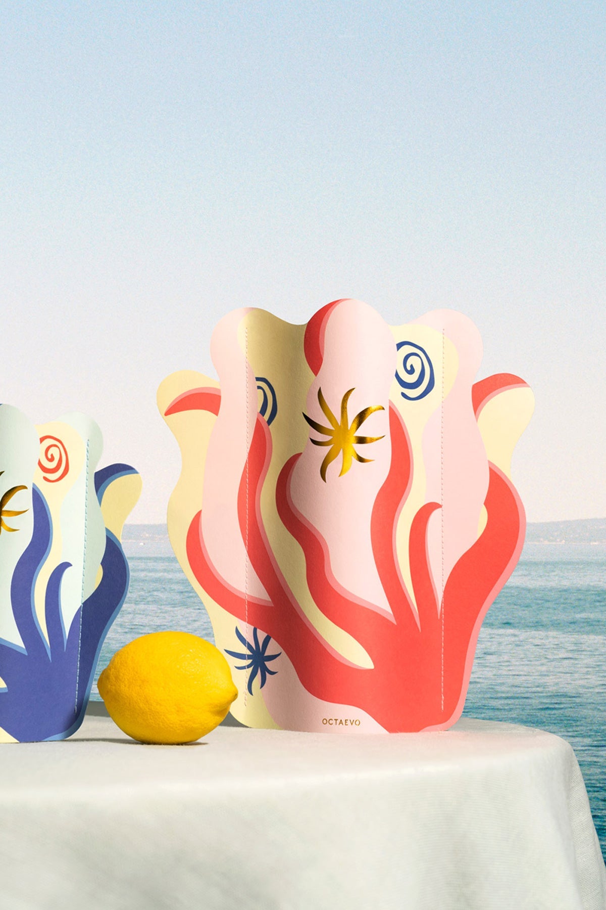 Le mini vase en papier Amalfi par Octaevo présente des motifs abstraits colorés inspirés de la côte amalfitaine.