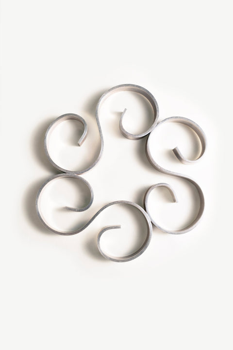 Christofle Arabesque Silver Trivet strips form spirals in a circle on a white background.