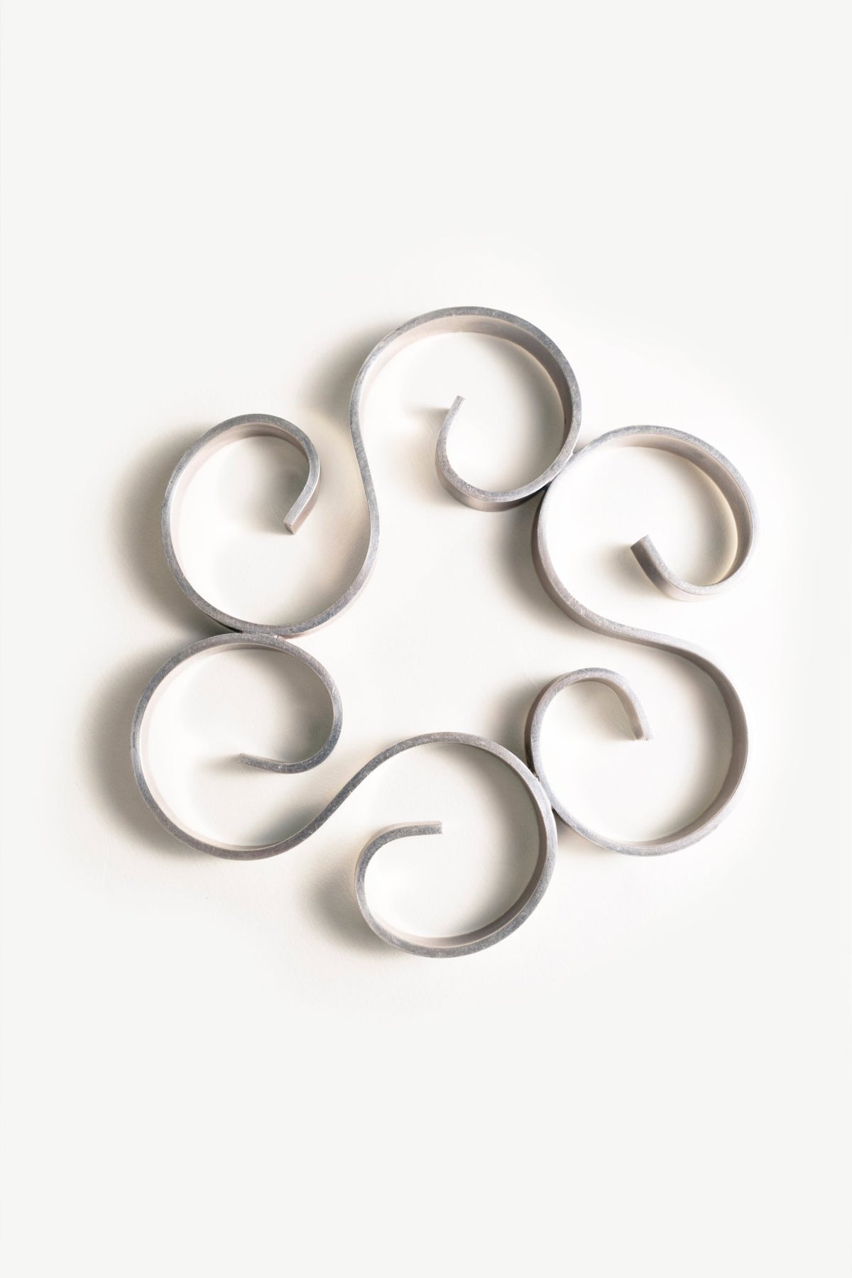 Christofle Arabesque Silver Trivet strips form spirals in a circle on a white background.