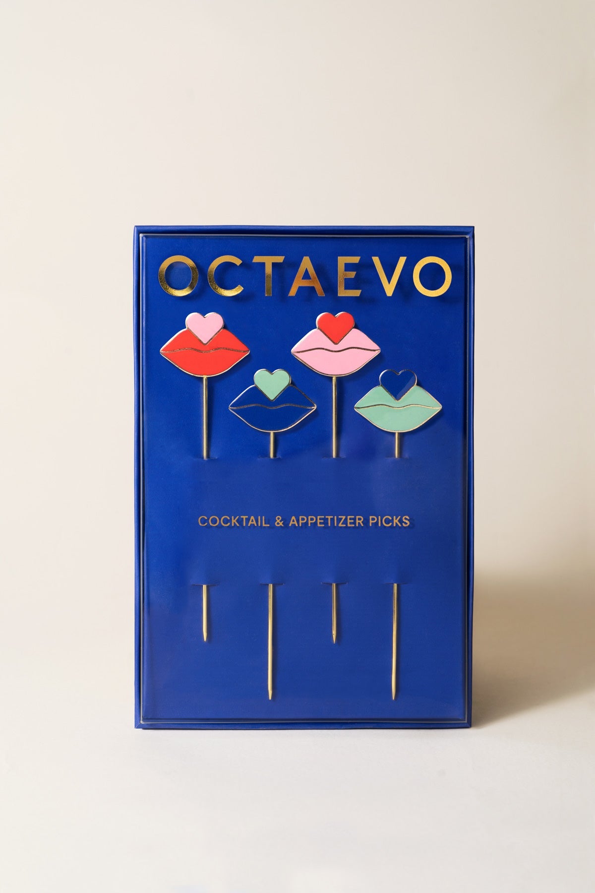 A blue OCTAEVO box holds a set of 4 Beso gold-plated, lip-shaped cocktail and appetizer picks.