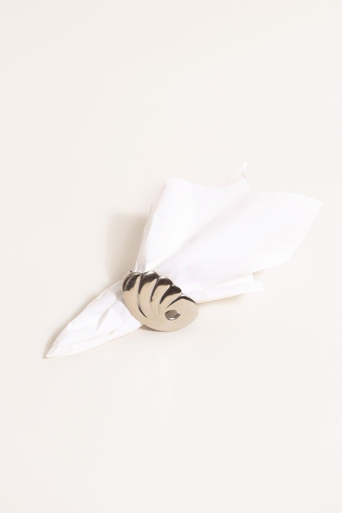 A white napkin is held by an Octaevo Bird Napkin Ring, set of 2—stylish silver decor for your dining table.