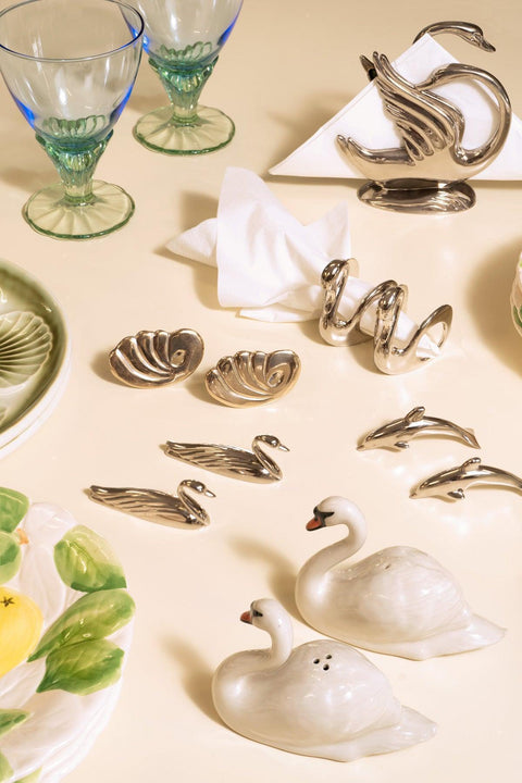 OCTAEVO Shell Napkin Rings (Set of 2), swan dishes, and glass goblets arranged for elegant dining on a cream surface.