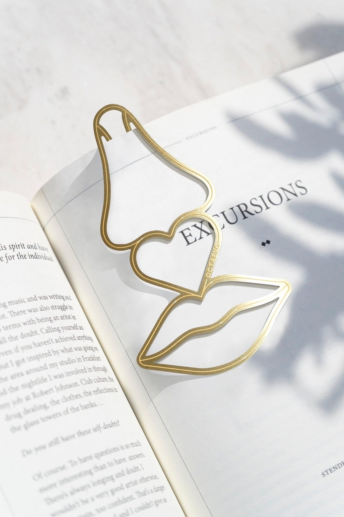 Octaevos Bookmark Beso—gold metallic nose, heart, and lips—adds poetic charm to your sunlit pages.