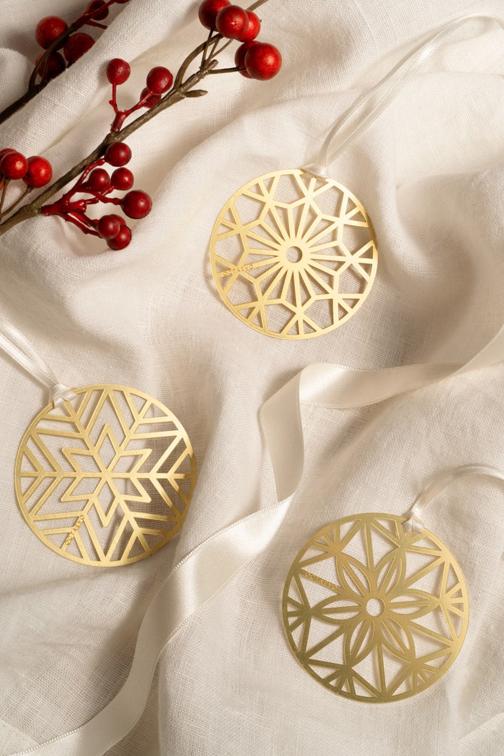 OCTAEVO Christmas Bauble Bookmark in burgundy, styled on white fabric with festive red berries in the corner.