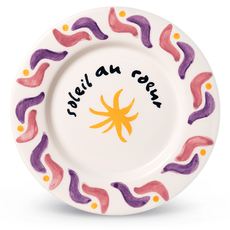 Cala Secreta Plate by Octaevo: white ceramic with a sun, handwritten text, and wavy pink and purple rim.