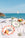 Two Octaevo Cala Secreta plates with fruit at a beach picnic, a sailboat on the blue sea in the background.