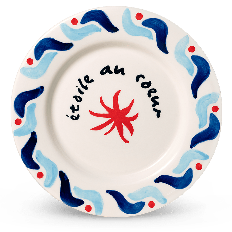 The Cala Secreta Plate by Octaevo is a ceramic plate with blue seaside motifs and étoile au coeur script.