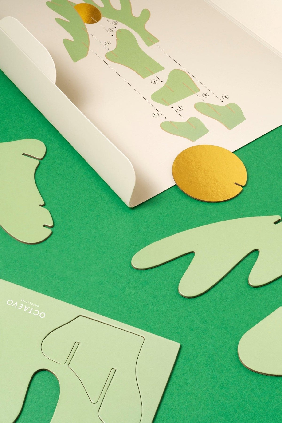 The Earth Paper Sculpture by Octaevo features green and gold sun shapes for artistic decor with easy assembly.