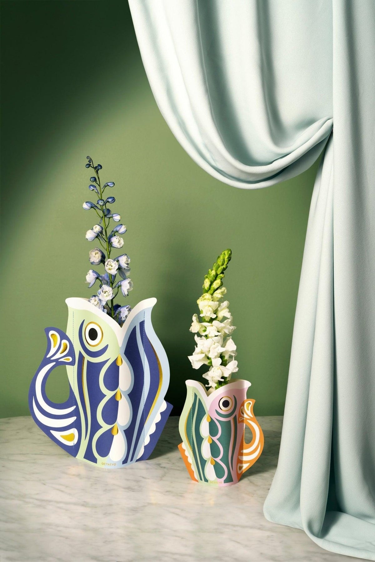 Pair of Fish Paper Vases in different colors displayed as table centerpiece with flowers in setting.