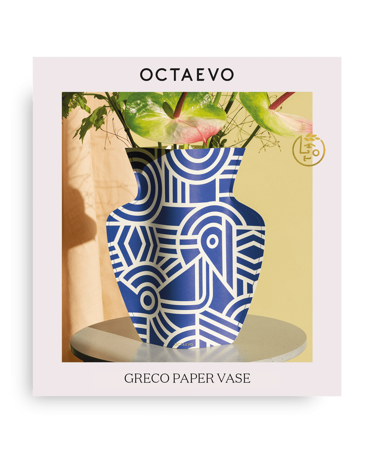Un vase en papier Greco OCTAEVO méditerranéen, géométrique, bleu et blanc, avec des feuilles vertes et roses.