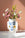 The OCTAEVO Janus Paper Vase features a blue abstract face and holds pink flowers on marble against a pink wall.