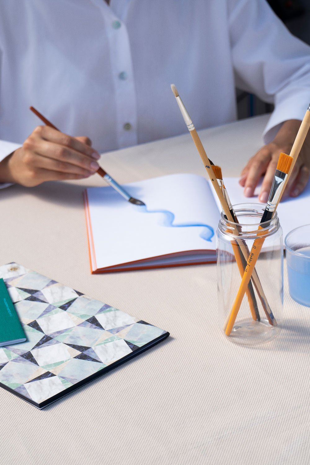 There is a blue OCTAEVO Marble Notes on the table, while someone else is drawing in another notebook.