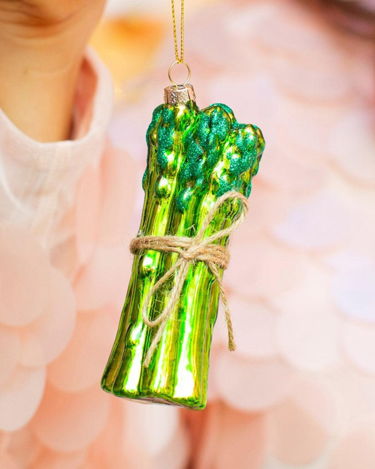 The Octaevo Merry Greens Baubles (Pack of 3) features a shiny asparagus ornament tied with twine and gold string.