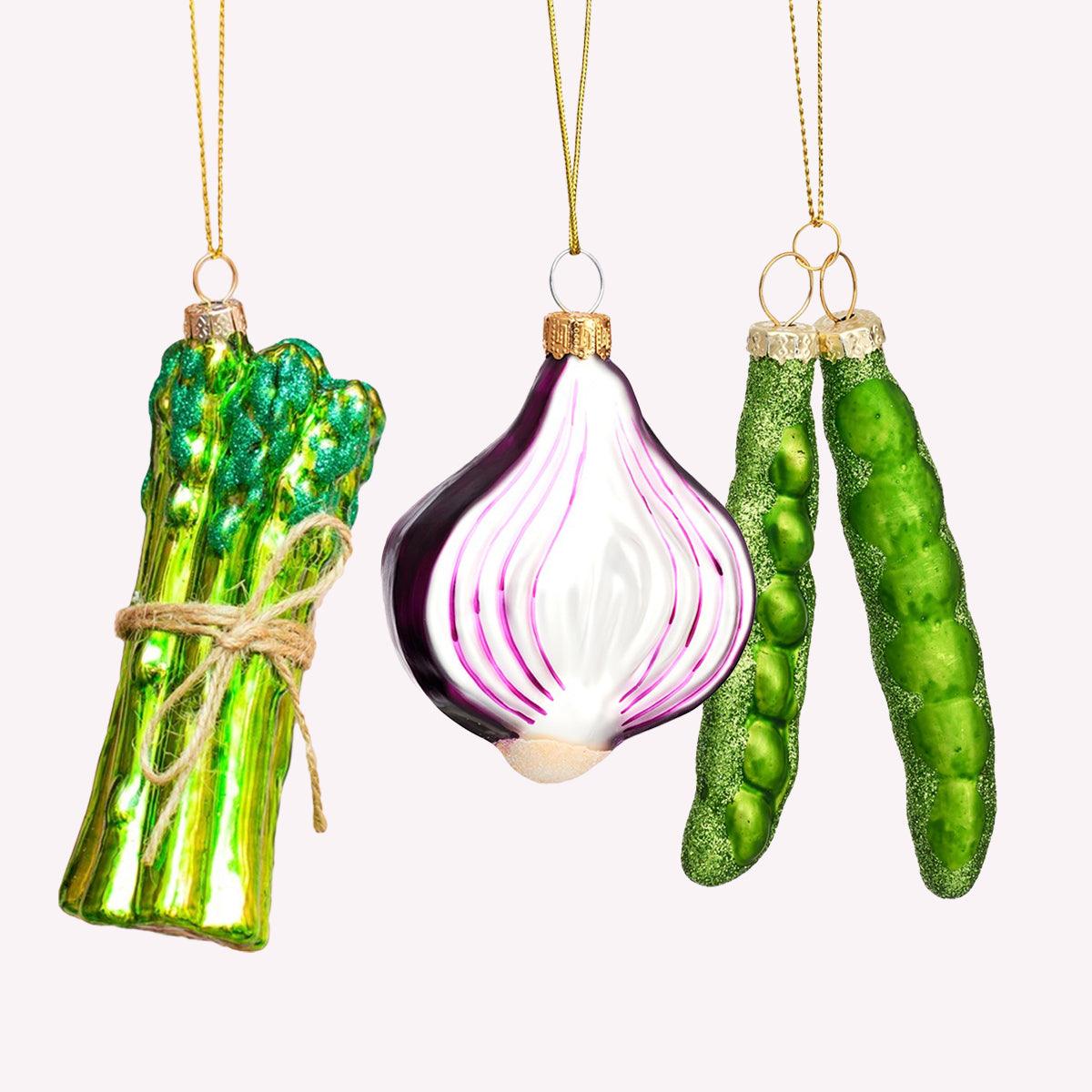 Octaevo’s Merry Greens Baubles (Pack of 3) includes glass asparagus, red onion, and pea pod ornaments with gold strings.