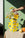 A hand arranges flowers in the OCTAEVO Nazar Paper Vase with eye motifs, on a sunny table with oranges.