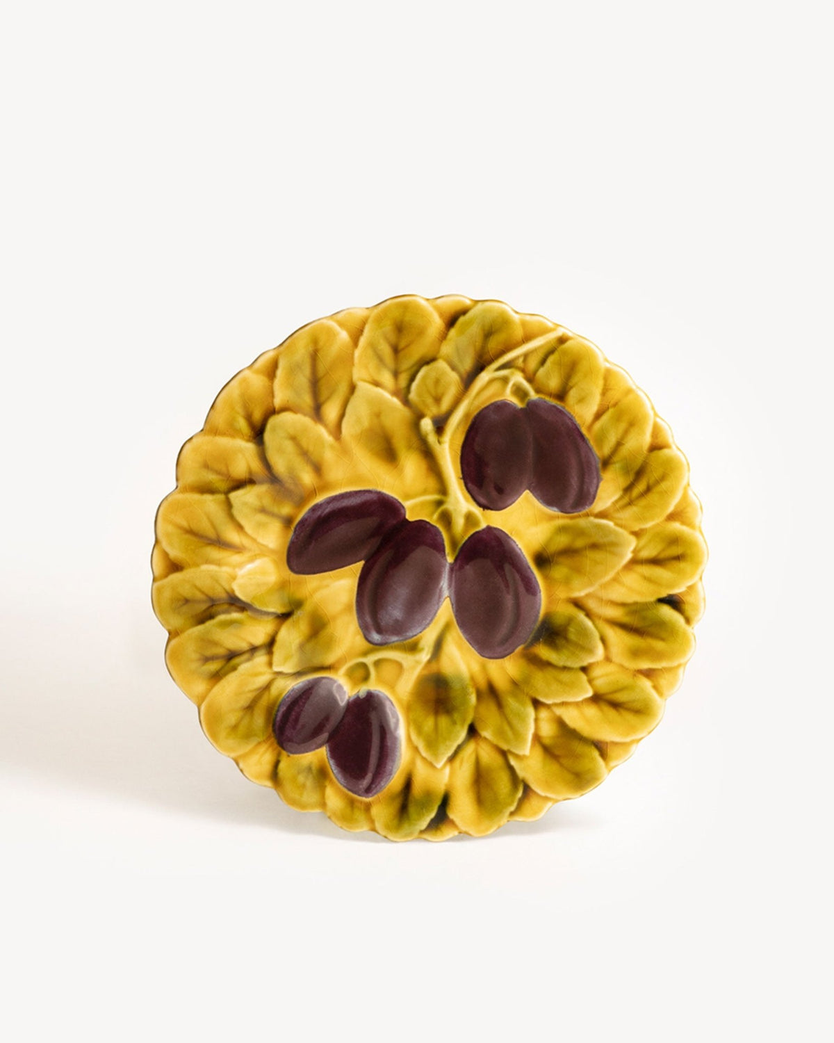 The OCTAEVO Plum Majolica Plate, round and yellow with raised leaf and plum designs, is shown on a white background.