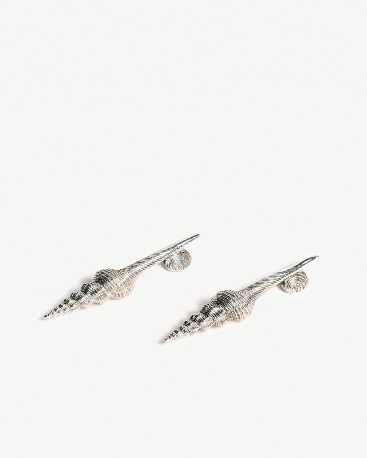 Pair of silver seashell knife rests on a white background