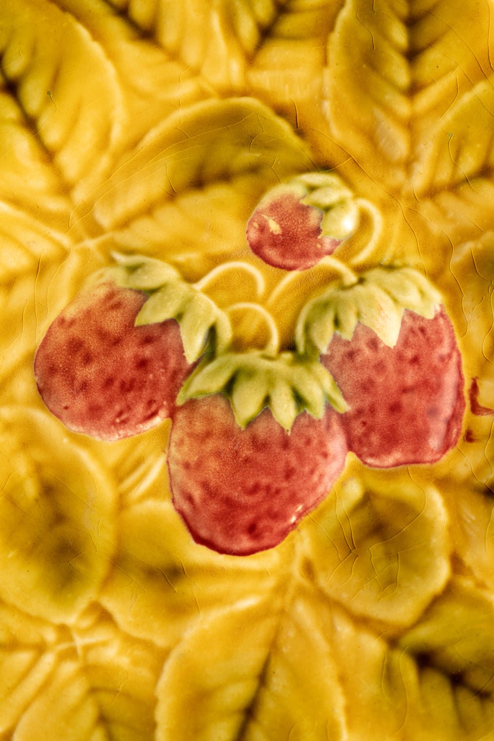 Close-up of OCTAEVO’s Strawberry Majolica Plate featuring red strawberries and green leaves on yellow.