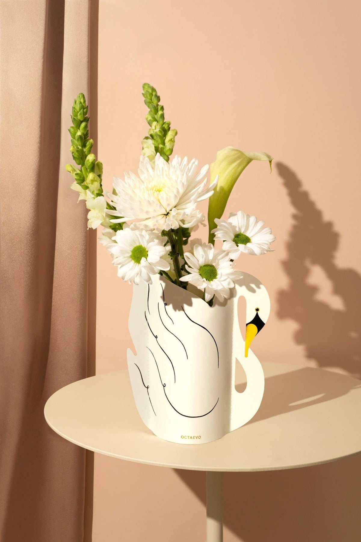 Octaevos Swan Mini Paper Vase holds white blooms and greenery, adding a surreal art touch to your round table.