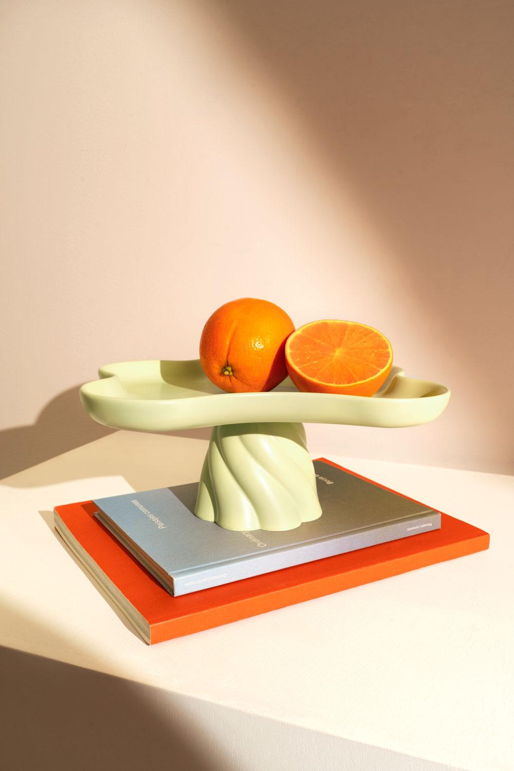 A light mint Octaevo Templo High Tray holds oranges and sits on books against a warm, minimal backdrop.