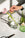 A hand places a pink tulip in the Agave Glass Container Large by OCTAEVO on a marble table, scissors nearby.