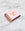 A pink OCTAEVO Apollo Matches box with gold foil accents lies on white marble, blue-tipped matches peeking out.
