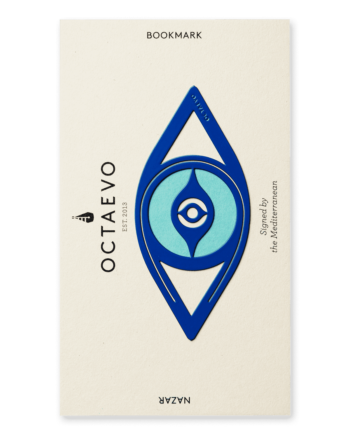 The Bookmark Nazar by OCTAEVO is a blue and turquoise Mediterranean eye brass bookmark on a cream card.