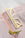 The gold OCTAEVO Bookmark Plein Soleil, shaped like sunglasses, rests on an open book beside a flower.