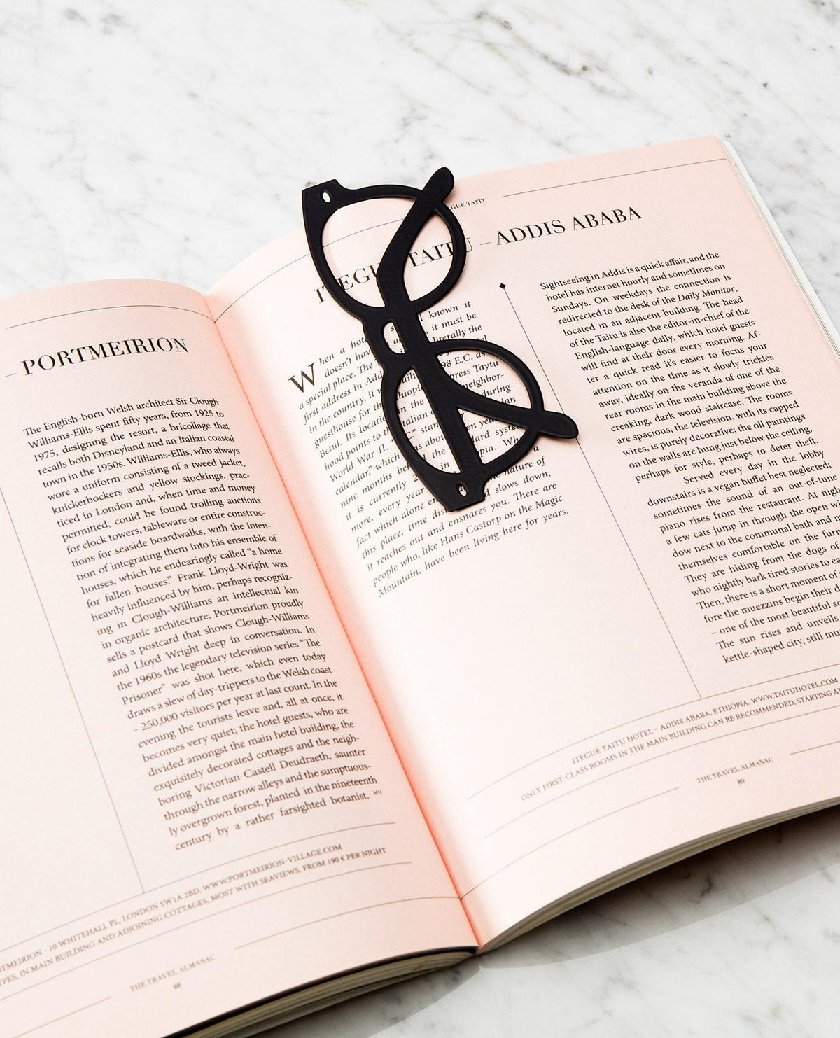 The black OCTAEVO Bookmark Riviera rests on an open magazine, adding style to a marble surface.