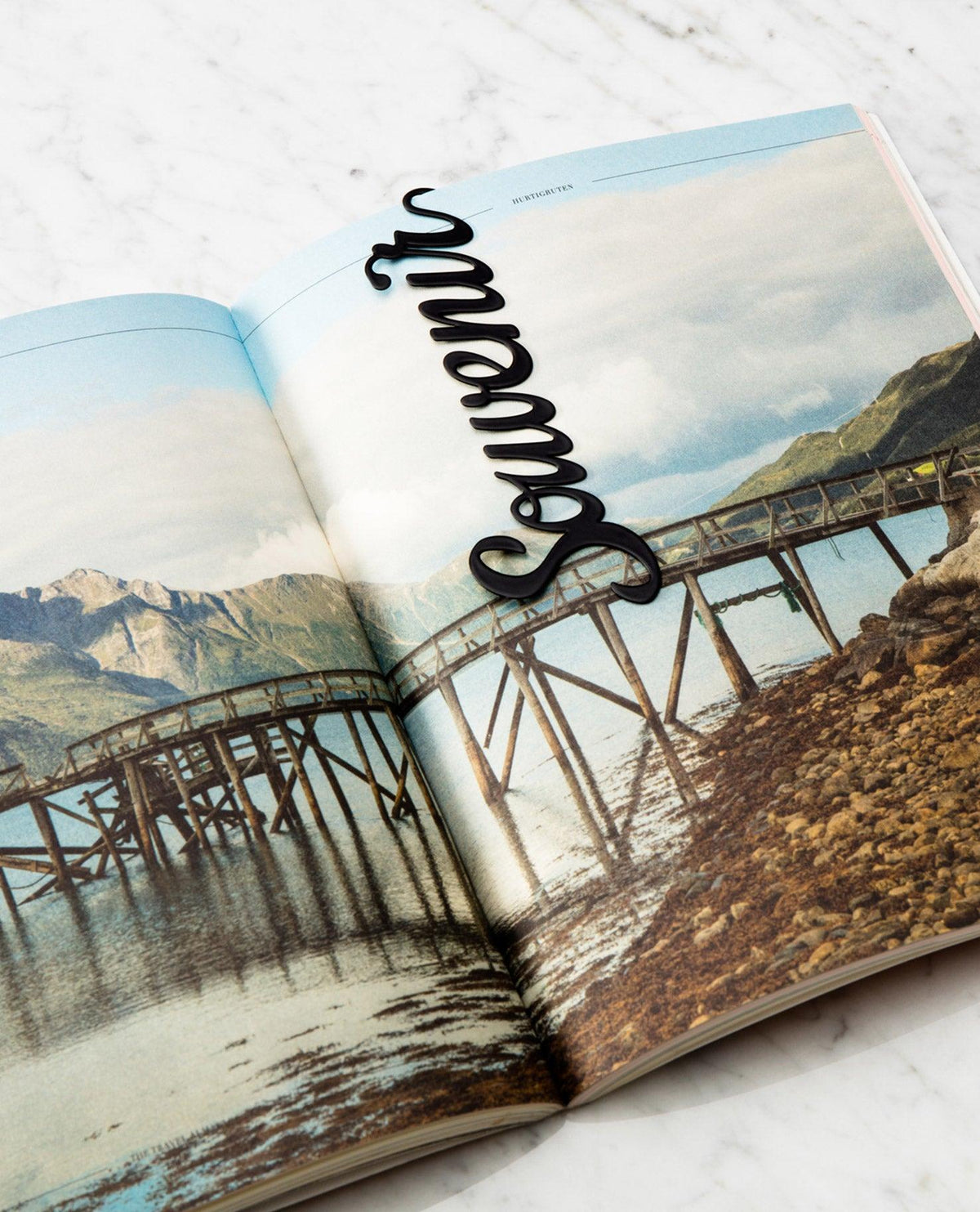 Open magazine with a photo of a wooden bridge; OCTAEVO Bookmark Souvenir in black script for collectors.