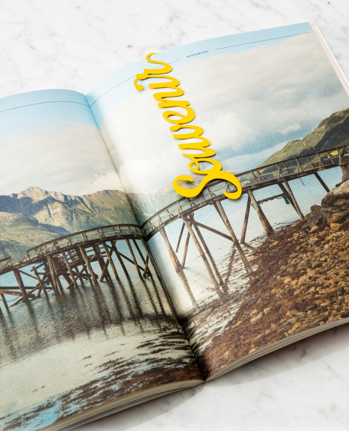 Open magazine with a photo of a wooden bridge; OCTAEVO Bookmark Souvenir in bold yellow script for collectors.