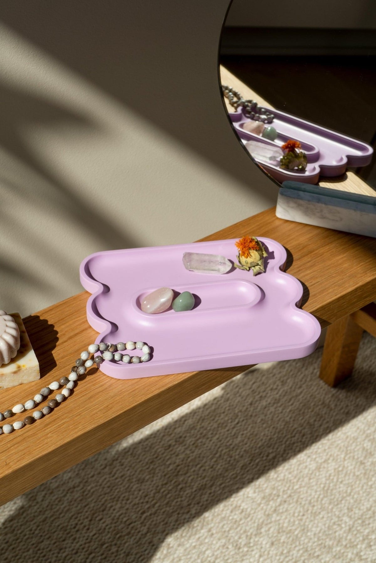 Purple Catchall Templo Wave by Octaevo—minimalist tray with crystals, beaded necklace & flower reflected in a mirror.