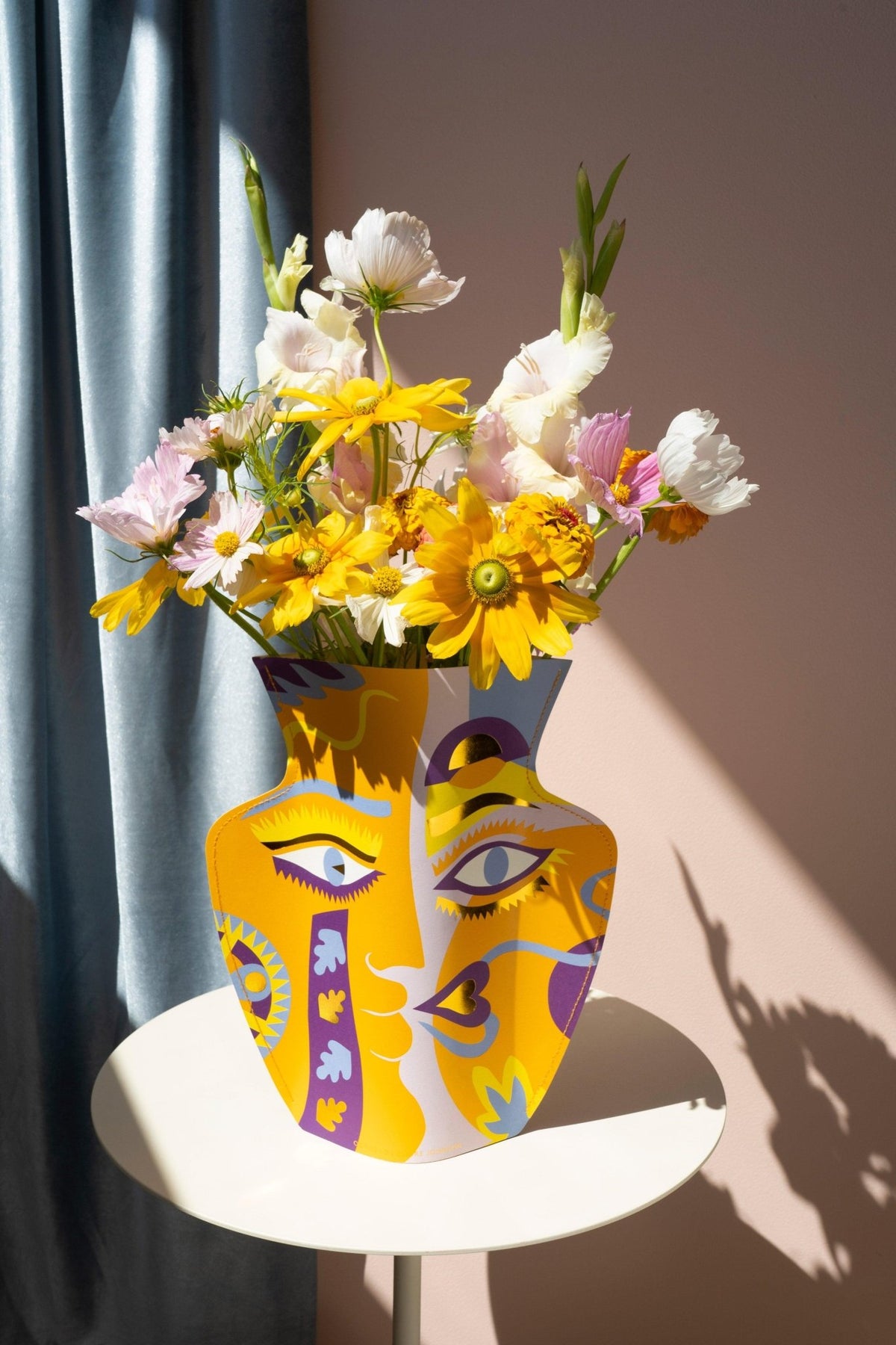 The orange Octaevo Claire Johnson Paper Vase features a face design and bright colors, perfect for displaying flowers. 